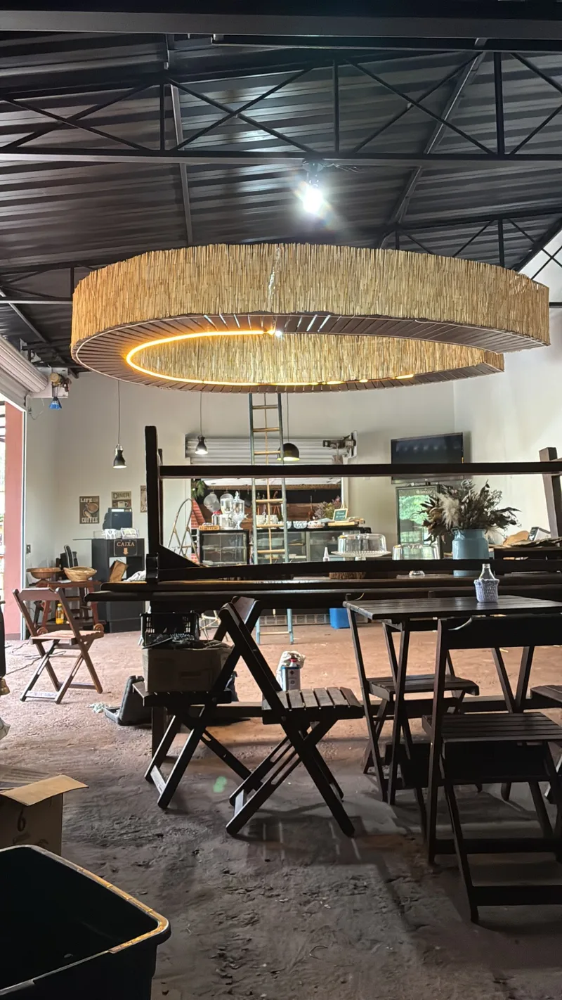 Salão do café com mesas de madeira e lustre de palha